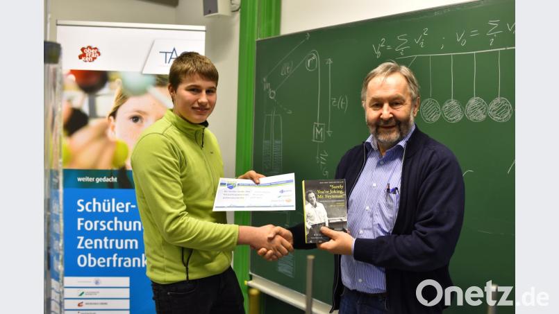 Mit einer Ehrenurkunde und einem autobiographischen Buch von Nobelpreisträger Richard P. Feyman würdigt Professor Walter Zimmermann (rechts) das Abschneiden von Lorenz Märker vom Gymnasium Eschenbach beim Regionalentscheid der Jungphysiker. Bild: exb