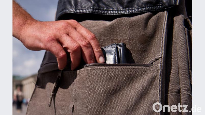 Während ihres Einkaufs stiehlt ein Dieb einer Frau die Geldbörse aus der Einkaufstasche. Symbolbild: Daniel Naupold/dpa