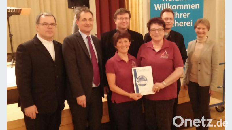 Stolz halten (vorne, von links) Bücherei-Leiterin Claudia Schnödt und ihre Kollegin Ilse Diertl die Verleihungsurkunde in den Händen. Mif ihnen freuen sich (von links) Domkapitular Heinrich Hohl, geschäftsführender Direktor Stefan Eß vom St. Michaelsbund, Dekan Marek Flasinski, Weihbischof Herwig Gössl und Diözesanbibliothekarin Melanie Dirauf. Bild: exb