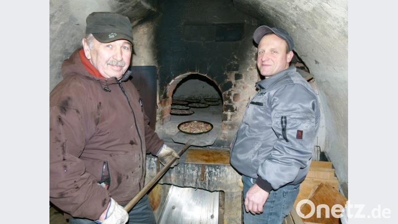 Heiß begehrt sind die frischen Zwiebelkuchen der Backofengemeinschaft, die (von links) Albert Kopp und Sigi Seidl aus dem Ofen holen. Bild: rn