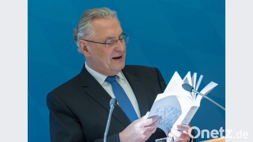 Der bayerische Innenminister Joachim Herrmann blättert auf einer Pressekonferenz im neuen Statistischen Jahrbuch. Bild: Peter Kneffel/dpa