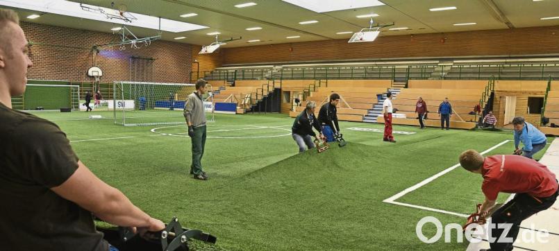 Ein eingespieltes Helfer-Team sorgt dafür, dass der Kunstrasen zur Zufriedenheit der Fußballer richtig verlegt wird. Bild: no