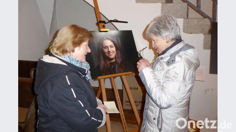 Eine „Patin“ (links) erläutert im Gottesdienst einer Besucherin das Schicksal der abgebildeten Iranerin Hoda. Bild: fsb