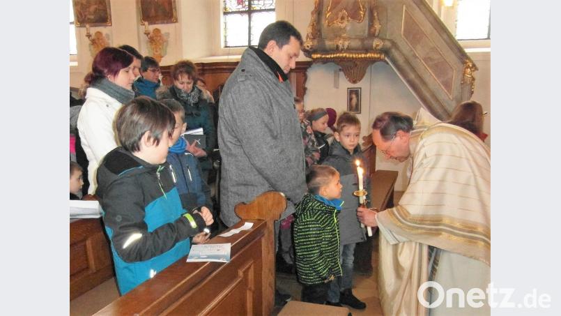 Mit vor dem Gesicht gekreuzten brennenden Kerzen spendet Pfarrer Heribert Stretz (rechts) auch den Kindern den Blasiussegen. Bild: hl