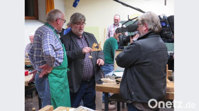 Hubert Rothmeier (links) erklärt Paul Enghofer vom BR (Zweiter von links) sein geschnitztes Spielzeug. Beim Ausschlag des Pendels bewegt der kleine Bär seine Arme. Organisiert hatte den Besuch der Vorsitzende der Schnitzergemeinschaft, Reinhold Gietl (im Hintergrund). Bild: ow