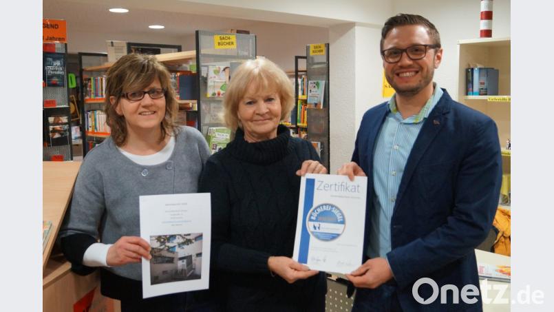 Strahlende Gesichter in der Gemeindebücherei: Bürgermeister Ernst Lenk übergibt Leiterin Marieluise Uebelacker das Zertifikat mit dem Bücherei-Siegel in Gold des Sankt-Michaelsbunds. Links Mitarbeiterin Annemarie Fink, die den Jahresbericht 2018 erstellt hat. Bild: du