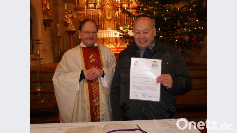 Pfarrer Heribert Stretz überreicht Karl-Heinz Meyer die Dankurkunde von Bischof Rudolf Voderholzer und der Bischöflichen Finanzkammer für 30 Jahre Mitarbeit in der Kirchenverwaltung. Bild: exb