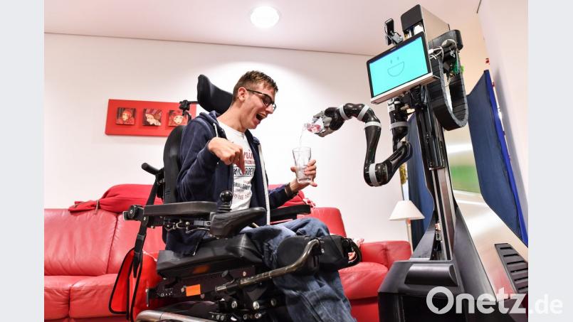 Ein Pflege-Roboter schenkt einem körperbehinderten Mann ein Glas Wasser ein. Bild: agentur_dpa