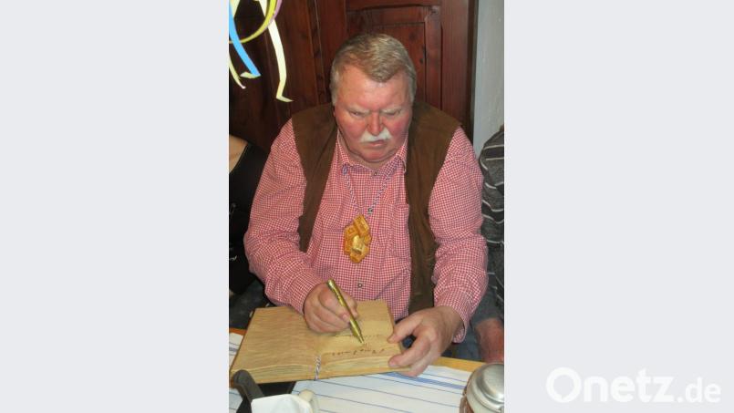 Schnitzer Alfons Kistenpfennig setzt seine Unterschrift mit goldenem Stift in das hölzerne Zoiglordensbuch. Bild: ui