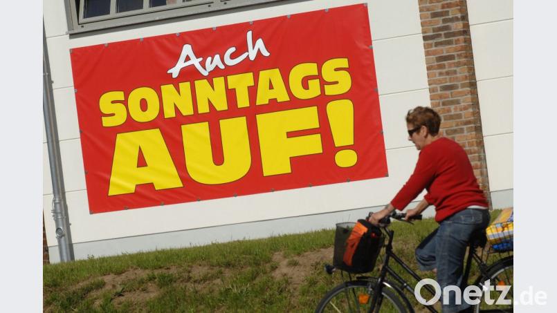 Eine Radfahrerin fährt an einem großen Plakat mit der Aufschrift "Auch Sonntags auf" vorbei. Foto: Stefan Sauer/Archiv Bild: Stefan Sauer