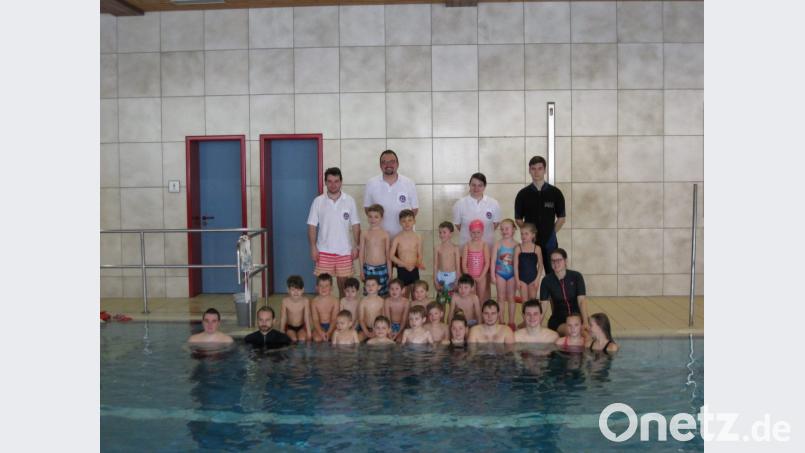 Stolz präsentieren sich die 18 Kinder mit ihren Ausbildern und den Vorsitzenden der Pfreimder Wasserwacht, Wolfgang Lotter (hinten, Zweiter von links), nach dem erfolgreich absolvierten Schwimmkurs im Hallenbad Nabburg. Zwölf von ihnen konnten das &quot;Seepferdchen&quot; in Empfang nehmen. Bild: hir