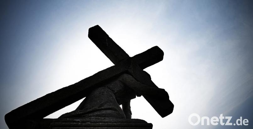 Unter blauem Himmel und gegen die Sonne zeichnet sich eine Jesusstatue unter dem Kreuz ab. Bild: Nicolas Armer/dpa