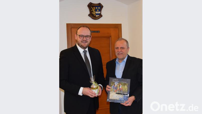 Landkreischef Andreas Meier (links) überreicht Peter Schobert, neuer Leiter des Eschenbacher Gymnasiums, ein Geschenk. Bild: exb