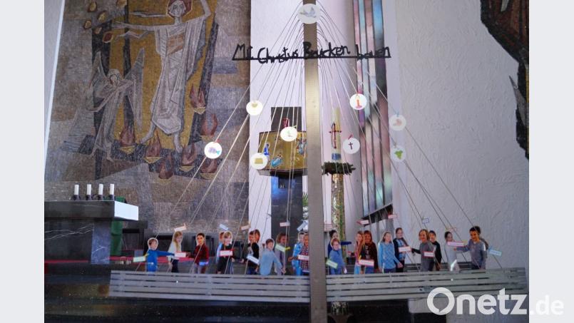 Mit Christus Brücken bauen“ steht als Motto über dem großen Brückenbauwerk im Modell, auf dem sich die 22 Kinder aus Papier gebastelt und mit ihren Namen versehen der Gemeinde vorstellen. Bild: du