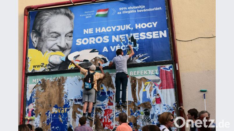 Aktivisten zerreißen am 12. Juli 2017 in Budapest ein Plakat der Kampagne gegen den US-Mäzen George Soros. Schon damals befeuerte die ungarische Regierung den Antisemitismus. Bild: Pablo Gorondi/ap/dpa