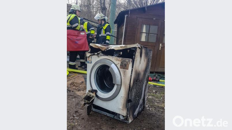 Ein technischer Defekt ist wohl die Ursache für den Brand einer Waschmaschine in Burggrub. Nach dem Löschen bringen die Einsatzkräfte den „Übeltäter“ ins Freie. Bild: rw
