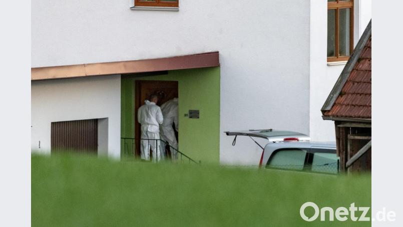 Beamte der Spurensicherung betreten ein Wohnhaus, vor dem ein Leichenwagen steht. Bild: Armin Weigel
