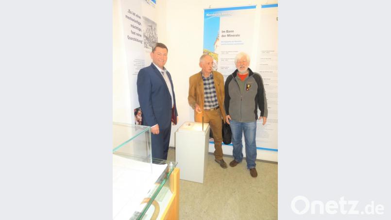 Erich Keck (Mitte) und Rupert Hochleitner (rechts) schenken Bürgermeister Rainer Rewitzer einen Stein des Minerals „Keckit“. Bild: tu