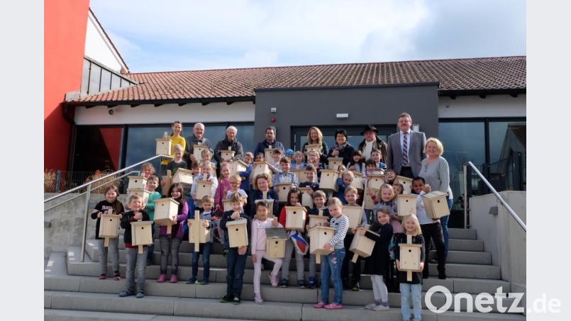 Die Erstklässer zeigen stolz ihre Nistkästen, die ihnen von den Mitgliedern der Vogelfreunde, den Mitarbeitern des Bauhofes und Bürgermeister Hans-Martin Schertl (Zweiter von rechts) übergeben wurden. Bild: Stefanie Gradl