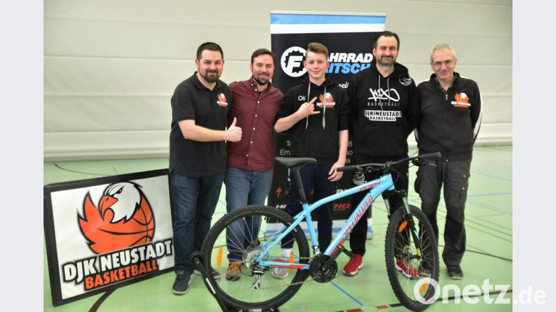 Hallensprecher Sebastian Dippold, Sponsor Ludwig Fritsch, Coach Gabi Ionescu und DJK-Abteilungsleiter Willi Merkl (von links) gratulieren Oli Roy (Mitte) zu seinem Volltreffer in der Halbzeit des Regiospiels der Neustädter Basketballer von der Mittellinie. Mit seinem Preis, dem Specialized-Mountainbike „Pitch“, dreht er gleich ein paar Runden. Bild: Tobias Schwarzmeier