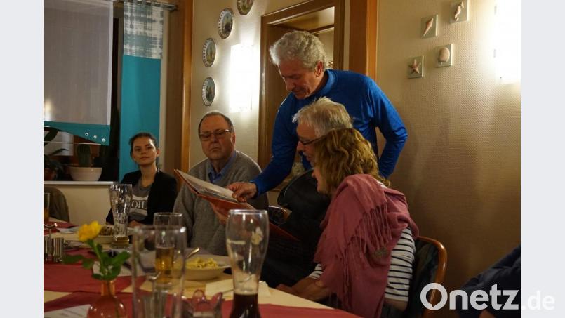 Günther Borutta (stehend) erklärt Stammtischgästen Fotos und Texte in der mitgebrachten Mappe (links Organisatorin Klára Halienková, europäische Freiwillige im CeBB). Bild: eib