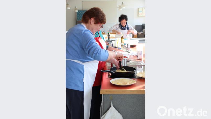 Hauswirtschaftsmeisterin Roswitha Hubmann erklärt den Kochkurs-Teilnehmerinnen und -teilnehmern, wie man Pfannkuchen in der Pfanne zubereitet, ohne dass sie kleben bleiben. Bild: Renate Scherer-Mende