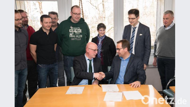 Schulleiter Anton Hochberger (sitzend, links) und Professor Axel Enders besiegeln die Partnerschaft per Handschlag. Bild: exb