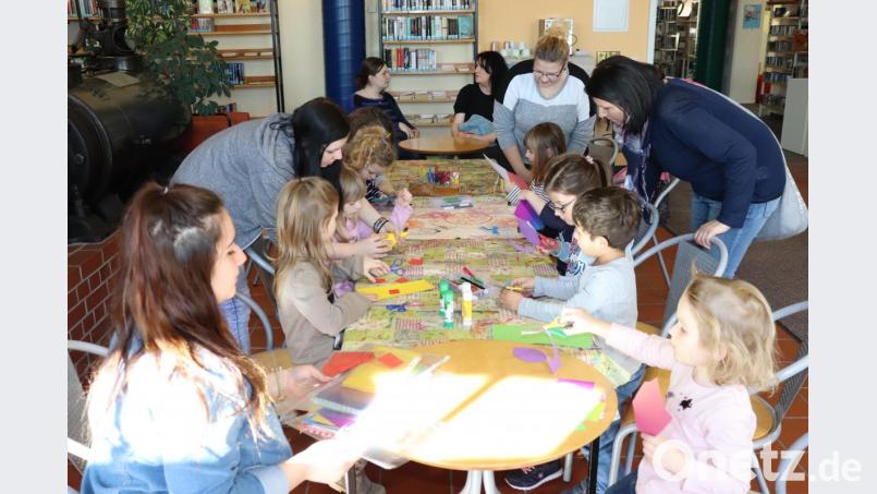 Kinderhaus-Erzieherin Eva Kohl (Zweite von rechts, stehend) sowie die beiden Praktikantinnen Kim Schraml (links) und Jaqueline Haid (Zweite von links, stehend) unterstützten die Bastelaktion in der Stadtbücherei. Bild: exb