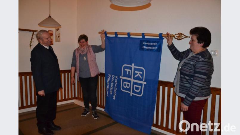 Die neue Fahne wurde von den beiden Vorsitzenden Lisa Ach und Hildegard Balk (von links) ausgerollt und Pfarrer Josef Most sowie den Frauen gezeigt. Bild: gi
