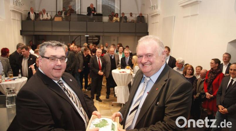 DGB-Regionsvorsitzender Christian Dietl (links) bedankte sich beim Referenten Helmut Fiedler (rechts) mit einem Tragl Bier. Zum Empfang waren in die Spitalkirche über 100 Gäste gekommen. Bild: Hirsch