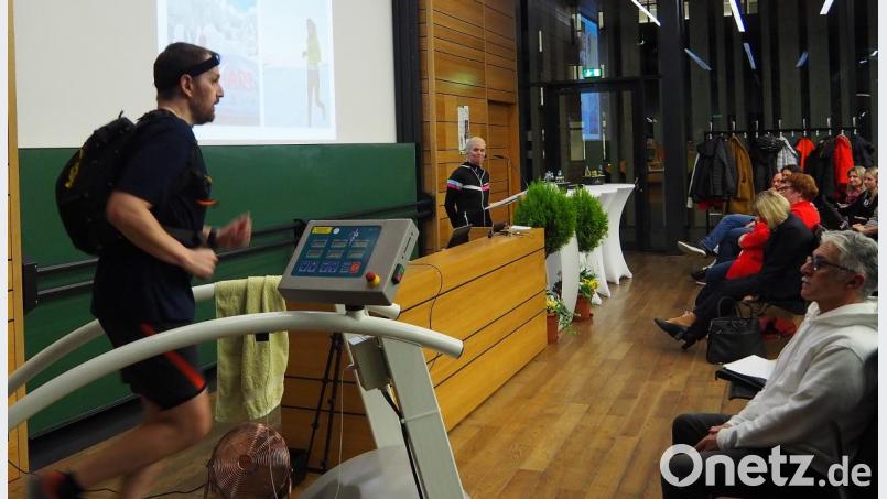 Redakteur Wolfgang Würth musste zehn Minuten lang auch den 7,5 Kilo-Rucksack schultern, den Extremläuferin Holly Zimmermann (am Rednerpult) beim Wüstenmarathon Amarathon de Sable getragen hatte. Bild: Bühner