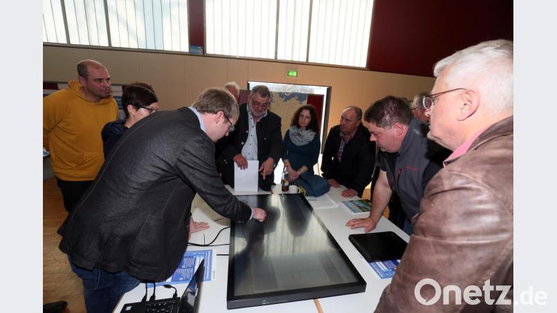 Eine Reihe von Anwohnern aus Lissenthan scharte sich mit Bürgermeister Armin Schärtl (Vierter von links) um das Display, auf dem Torsten Grampp (Dritter von links) von Tennet den Trassenverlauf erläuterte. Bild: Hösamer