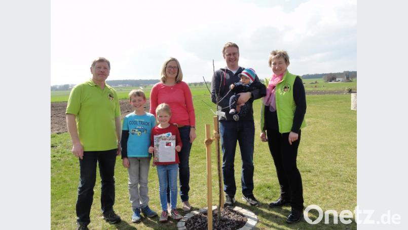 Stefan Gebhardt (Zweiter von rechts) mit dem kleinen &quot;Prinzen&quot; Jonas, Gattin Lisa sowie die Kinder Max und Charlotte (links daneben) freuen sich über den kräftigen Stammbaum, von dem sie hoffentlich bald leckere Äpfel ernten können. Josef Höllerl (links) und Christine Walter (rechts) vom Obst- und Gartenbauverein überreichen das Geschenk zur Geburt. Bild: jhö
