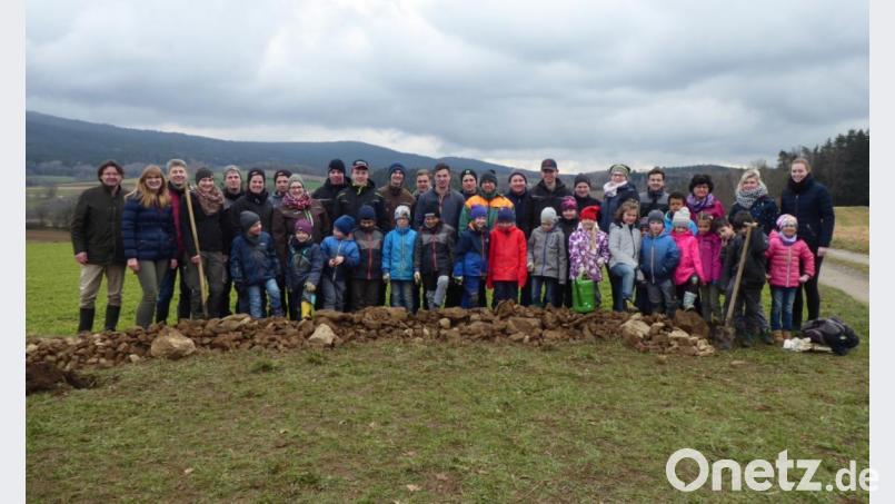 Im Vordergrund ist der Steinwall zu erkennen, den die Grundschüler für das Projekt angelegt hatten. Mit auf dem Bild sind auch die Studierenden der Landwirtschaftsschule sowie Betreuer, Lehrkräfte und weitere Beteiligte des Vorhabens, von dem Landschaftspflege und Artenschutz profitieren sollen. Bild: exb/Birgit Simmeth