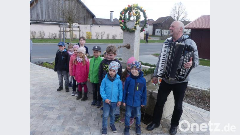 Angeführt von Musikant Gerd Retzer tragen Kinder den Osterschmuck zum Dorfbrunnen. Bild: rn