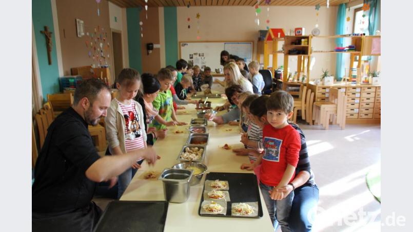 Unter der Anleitung von Kräuterkoch Andreas Meier (vorne links) durften die Kinder ihre Pizzas selbst belegen und natürlich dann auch essen. Das machte mächtig Spaß. Bild: frd