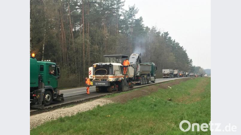 Die Großfräse trägt fortlaufend die oberste Asphaltschicht ab und spuckt sie auf die Sattelzüge, die in langer Reihe warten. Bild: Stefan Noll