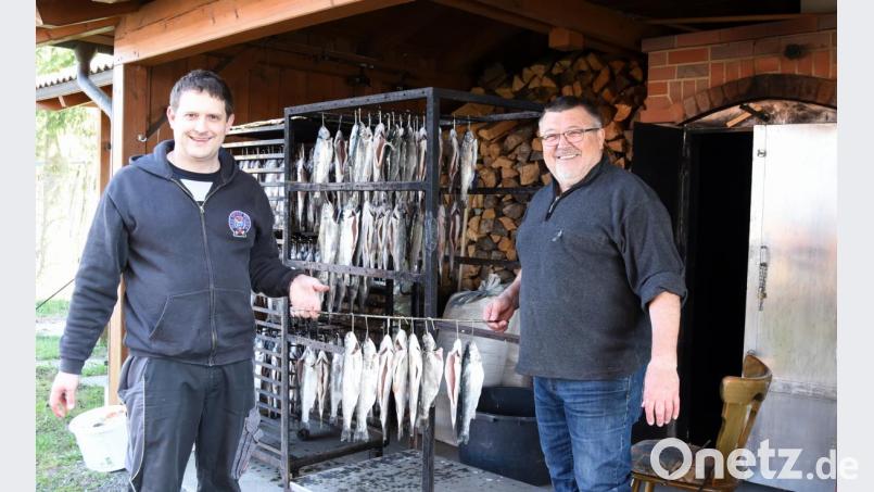 Vorsitzender Tobias Hacker (links) und Ehrenvorstand Dieter Pscheidt hängen die Fische an den Räuchergestellen auf. Bild: bgm