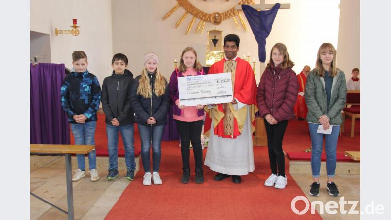 Die Firmlinge übergeben die Spende an Pater Charles. Bild: ral