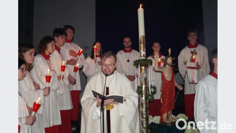 Pfarrer Thomas Stohldreier beim &quot;Exsultet&quot; vor der Osterkerze, dem Lobgesang auf die Osternacht. Die Ministranten formieren sich dafür zu einem Omega. Bild: du