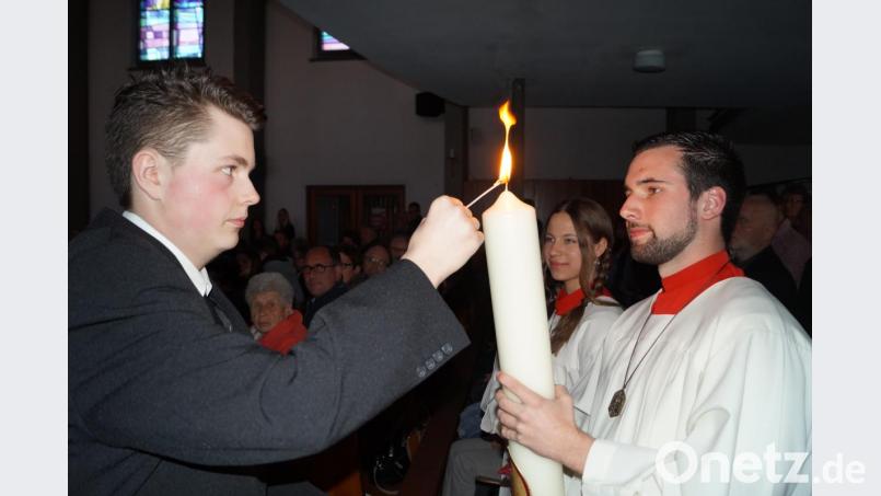 Oberministrant Johannes Wolf (links) entzündet die Osterkerze, die von Jonas Steiner (rechts) in die Kirche getragen wird. Bild: du