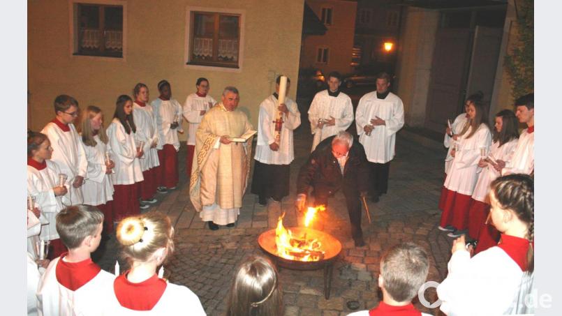 An der eisernen Feuerschale vor dem Kirchenportal wurde im Kreise der Ministrantenschar die Osterkerze entzündet. Bild: lg