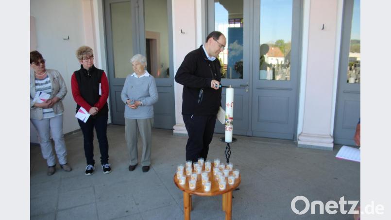 Der evangelische Pfarrer Gerhard Beck entzündet die Osterkerze vor der Halle auf dem Friedhof. Gläubige stellen ein Osterlicht auf die Gräber ihrer verstorbenen Angehörigen. Bild: sns