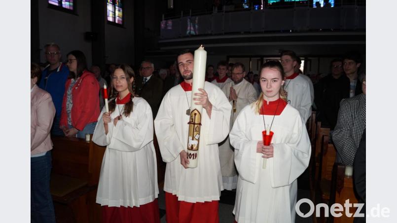 Jonas Steiner trägt die Osterkerze in die Kirche. Bild: du