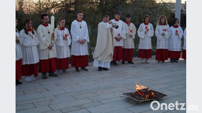 Pfarrer Thomas Stohldreier segnet auf dem Kirchplatz das Osterfeuer, bevor er mit seiner Ministrantenschar ins Gotteshaus einzieht. Bild: du