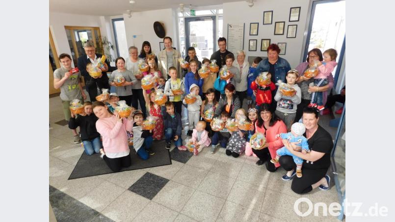 Caritasmitarbeiterin Dolores Longares-Bäumler (vorne, Dritte von rechts) und Bürgermeister Manfred Porschl (hinten, Zweiter von links) spielen Osterhase und beschenken Kinder aus der Gemeinde mit insgesamt 65 Osternestern. Bild: hai