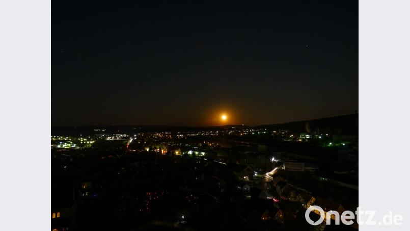 Das Bild entstand gegen 21 Uhr. Unten links ist ein Teil der Rosenberger Kirche zu sehen, daneben der Friedhof (kleine rote Lichter). Am Horizont geht im Osten der Mond auf. Rechts daneben die Mariahilfbergkirche von Amberg hell erleuchtet. Das Industriegebiet von Rosenberg ist vom Stromausfall nicht betroffen gewesen. Bild: Michael Rösl