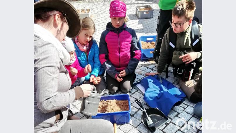 Geoparkrangerin Michaela Hoffer zeigt den Speichersdorfer Kindern, wie sie mit etwas Sand, Backpulver und Essigwasser einen Vulkan simulieren können. Bild: hai
