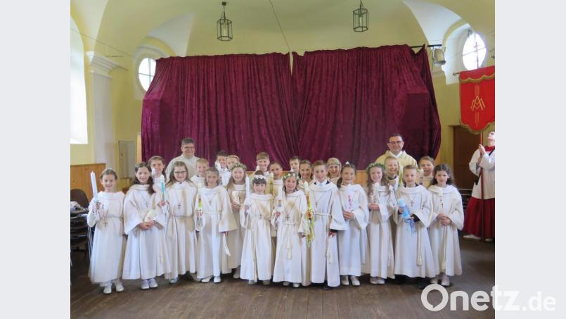 Nach der Weihe der Andachtsgegenstände in der Grabenkapelle präsentierten sich die 23 Erstkommunionkinder der Pfarrei Mariä Himmelfahrt in ihren festlichen Kommuniongewändern zusammen mit Stadtpfarrer Konrad Amschl (hinten rechts) und Gemeindereferent Jochen Gößl (hinten links). Bild: jzk