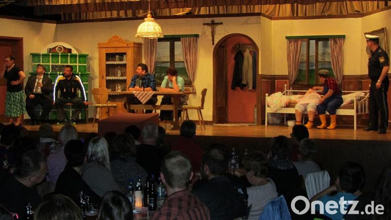 Bäuerin Loni nimmt das rettende Telefonat entgegen, daneben am Kachelofen Bauer Jakob und der Postbote Gustl, am Tisch Josef und Rosi Heiliger, auf der Bettkante Mucki und Xaver sowie ganz rechts Polizist Eduard. Bild: sck